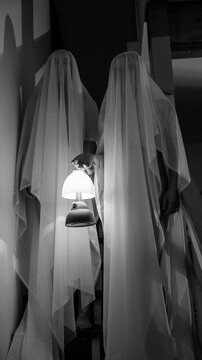 Two ghost figures on stairs holding lit lamp in dark indoor setting