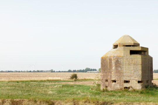 Concrete Coastal Pillbox Bunker in Rural Field With Distant Wind Turbines and Empty Landscape
