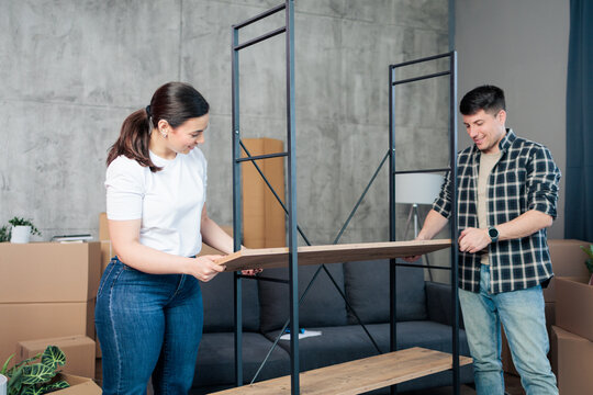 Young couple assembling new furniture in apartment relocation