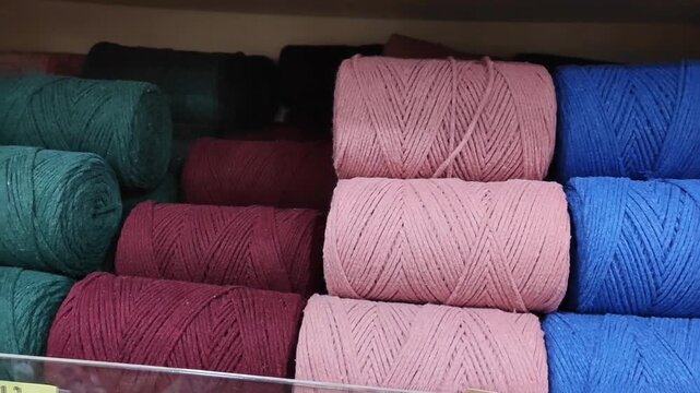Colorful spools of thick macrame cord neatly arranged on a store shelf, durable cotton rope for knitting and handcrafting