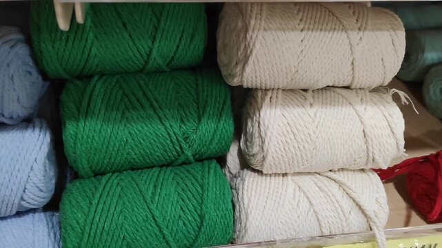 Colorful spools of thick macrame cord neatly arranged on a store shelf, durable cotton rope for knitting and handcrafting