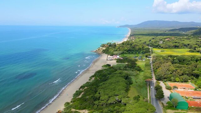Aerial view of Tuscan coastline with sandy beach, turquoise sea and pine forest, forward drone shot
