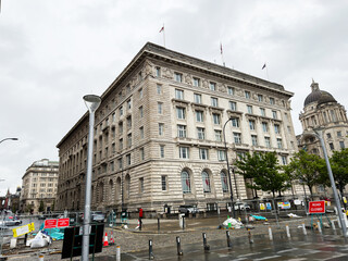 Historic neoclassical government building on the Liverpool, UK waterfront with stone façade, dome and construction barriers marking road closed during renovation in an urban city centre © AS Photo Family