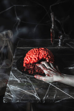 Brain-shaped cake with bleeding zombie hand for Halloween party