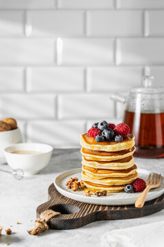 Stack of pancakes topped with fresh berries and honey