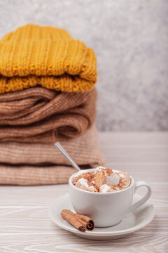 Hot chocolate with marshmallows and cinnamon sticks beside a stack