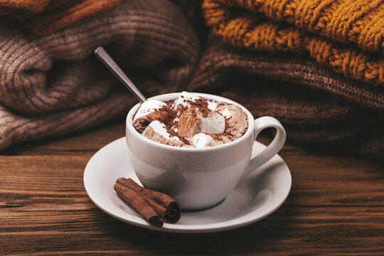 Hot chocolate with marshmallows and cinnamon sticks beside warm