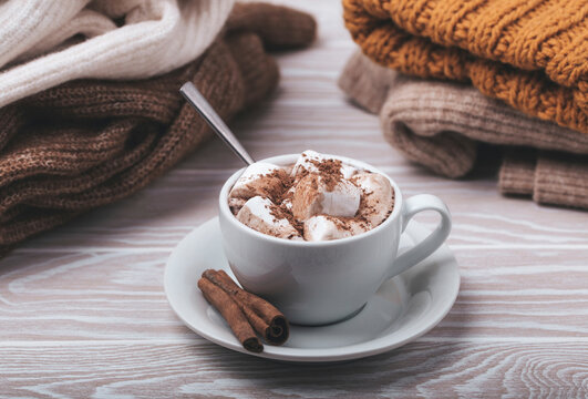 Hot chocolate with marshmallows and cinnamon sticks by warm clothes