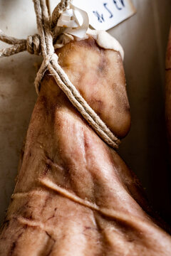 Raw air-dried ham hanging suspended by lace string close-up
