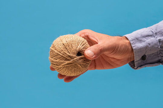 Hand holding natural jute twine ball. Ideal for sustainable packaging advertisements, DIY craft website banners, editorial packaging guides, and hobbyist marketing.