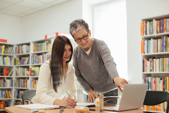 University student receiving help from tutor in library