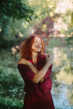 Woman with red hair embracing herself in autumn park