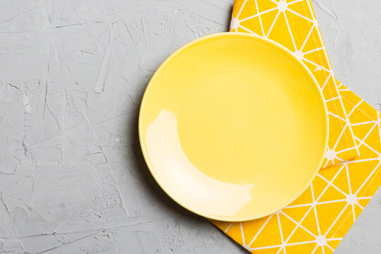 Top view on colored background empty round yellow plate on tablecloth for food. Empty dish on napkin with space for your design
