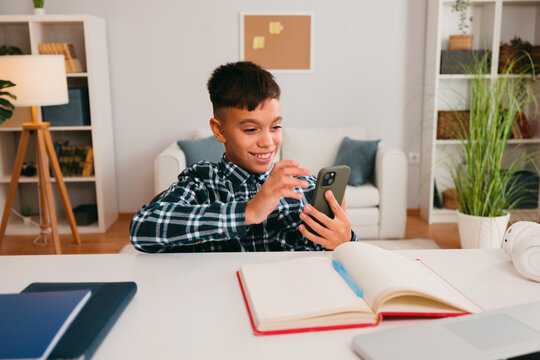 Boy using phone getting distracted from homework