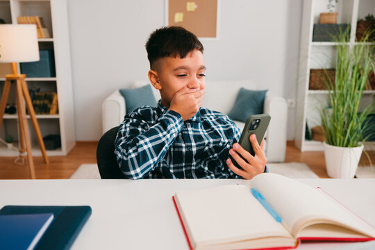 Boy covering mouth surprised while viewing smartphone