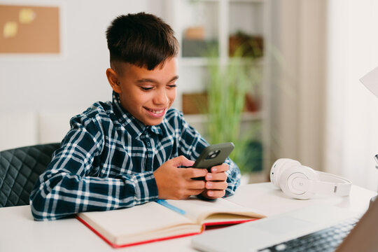 Young boy smiling while using smartphone for online learning