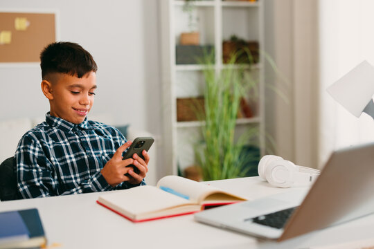 Boy using smartphone instead of doing homework