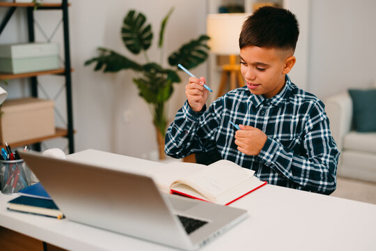 Young boy learning remotely using laptop and notebook