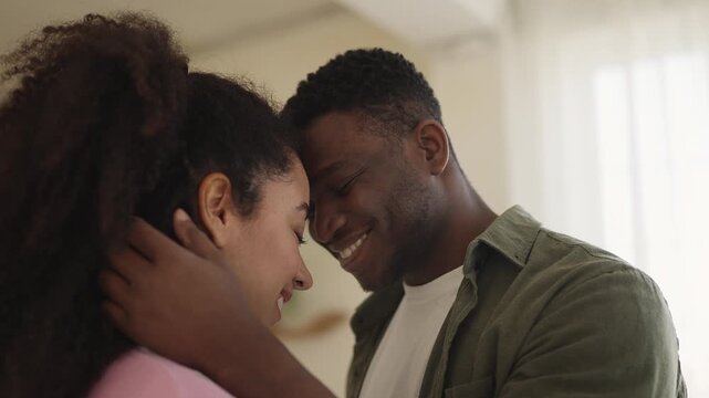 Happy African American man and wife touch foreheads, true love and care