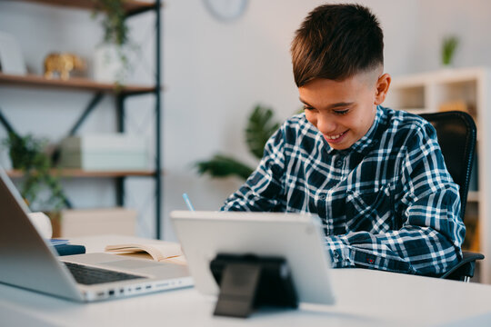 Young boy enjoying online learning and writing homework