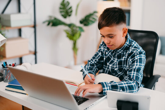 Young student learning from home using laptop and notebook