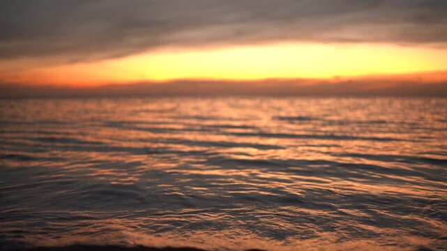 Resilient marine ecosystem showcases natural ocean tides crashing on shoreline during sunset twilight. Static low angle medium shot.