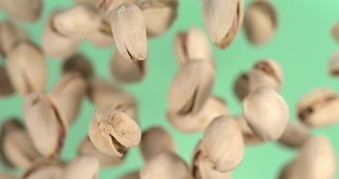 Pistachios falling in slow motion on green background top view