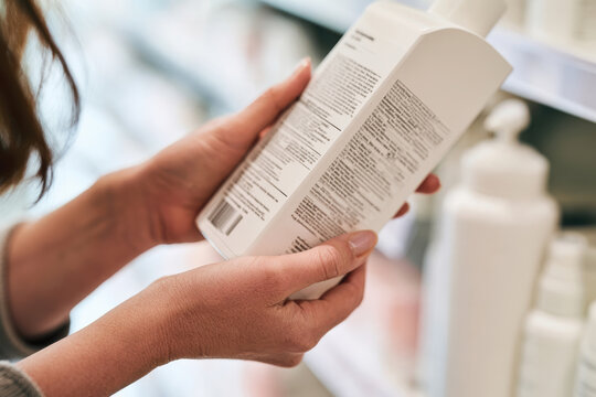 A customer intently reading the labels of cosmetic bottles, showcasing the awareness and importance of understanding ingredients in skin care and beauty products.