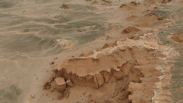 Aerial drone shot tracking over the deep eroded gullies, clay ridges, and striking red earth formations of the Flaming Cliffs in the Gobi Desert, Mongolia