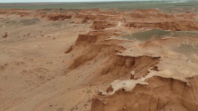 aerial drone fly above the wind-sculpted badlands, red clay hills, and expansive arid landscape of the Flaming Cliffs in Mongolia