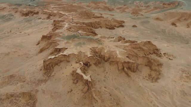 Close up aerial drone along the jagged edges of wind-swept red sandstone bluffs and ancient sediment layers at the Flaming Cliffs in the Gobi Desert, Mongolia