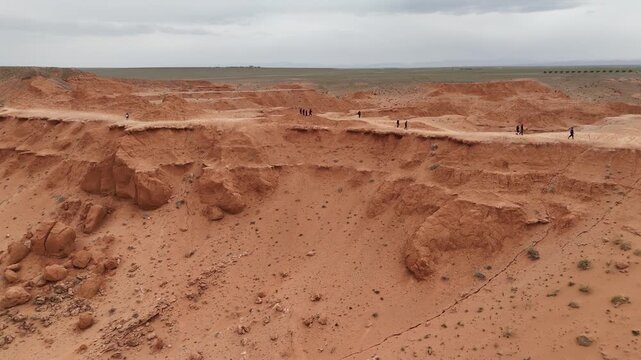 aerial view of tourist walking the path along the crest of the Flaming Cliffs in the Gobi Desert, Mongolia