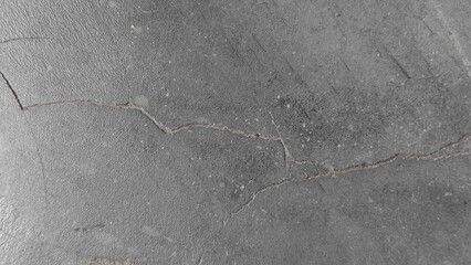 Dark gray cracked concrete floor surface with detailed texture and linear fissures for backgrounds. © riazul