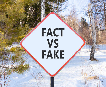 Fact vs versus fake words symbol. Concept words Fact vs Fake on beautiful white road sign. Beautiful winter forest background. Business and fact vs versus fake concept. Copy space.