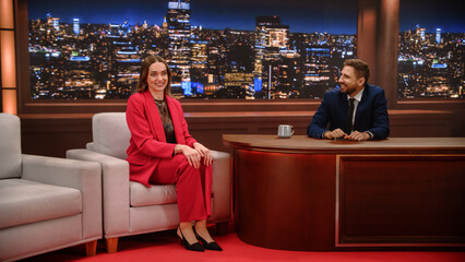 Evening Television Interview on Studio Set: Woman Guest Smiles on Armchair During Fun Talk as Male...