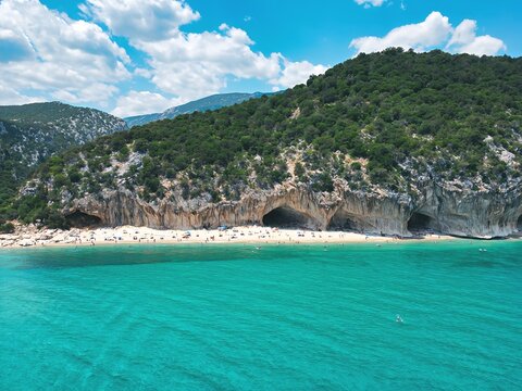 Aerial view of Cala Luna beach with limestone caves, turquoise sea and green cliffs, Gulf of Orosei, Sardinia, Italy