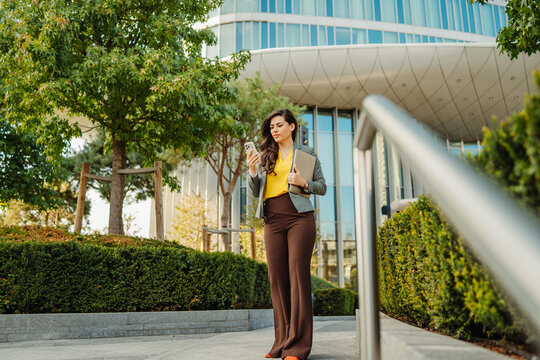 Businesswoman checking smartphone while walking in urban park