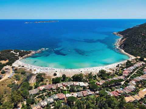 Aerial view of Cala Pira beach with white sand, turquoise bay, villas and green hills, Castiadas, Sardinia, Italy
