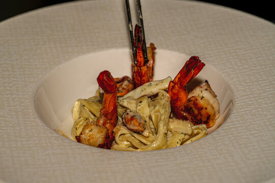 Classic Italian seafood pasta: hrimp fettuccine pasta served with creamy garlic sauce and fresh parsley on a plate.