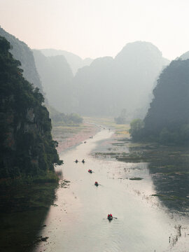 Aerial view of Tam Coc Bich Dong with small boats carrying people along the winding river surrounded by limestone karst mountains in Nam Hoa Lu, Ninh Binh, Vietnam.