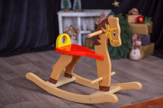 Classic Wooden Rocking Horse Toy on Floor with Christmas Decorations and Wrapped Gifts in Festive Holiday Room