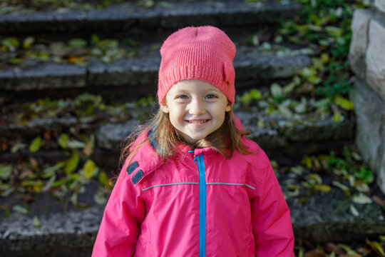 Smiling Little Girl in Pink Winter Hat and Jacket Outdoors. Happy Childhood Portrait