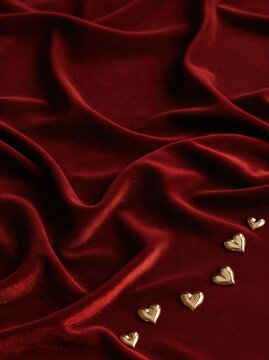 a rich deep burgundy velvet fabric surface with several small polished champagne gold metallic hearts 
