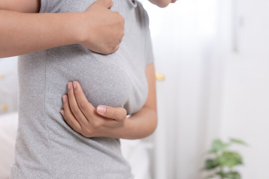 Woman suffering painful chest ache touching breast with sad worried expression during self examination