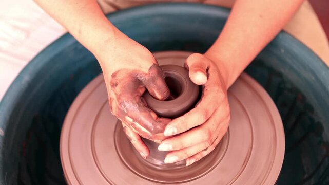 Potter's hands molding clay on a rotating pottery wheel