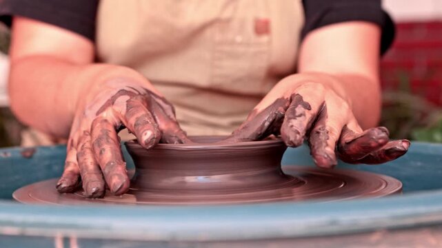 Potter shaping wet clay on a pottery wheel
