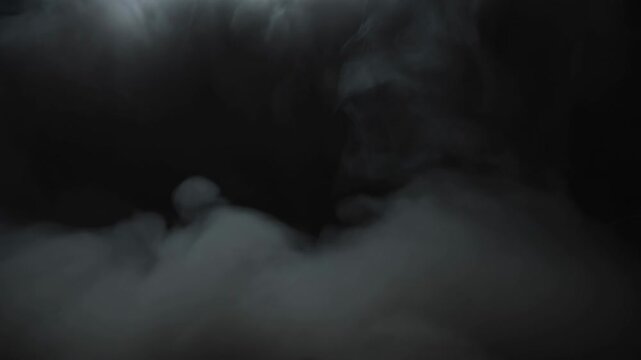 Gray smoke and fog billow and swirl against a nearly black atmospheric background. Cinematic title sequences, horror film promotion, and suspense trailers.