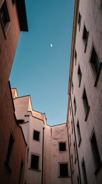 Looking Up Between Pastel Buildings at a Clear Sky