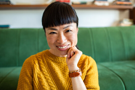 Smiling woman resting chin on hand at home