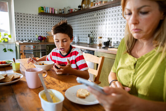 Boy using smartphone during breakfast at home